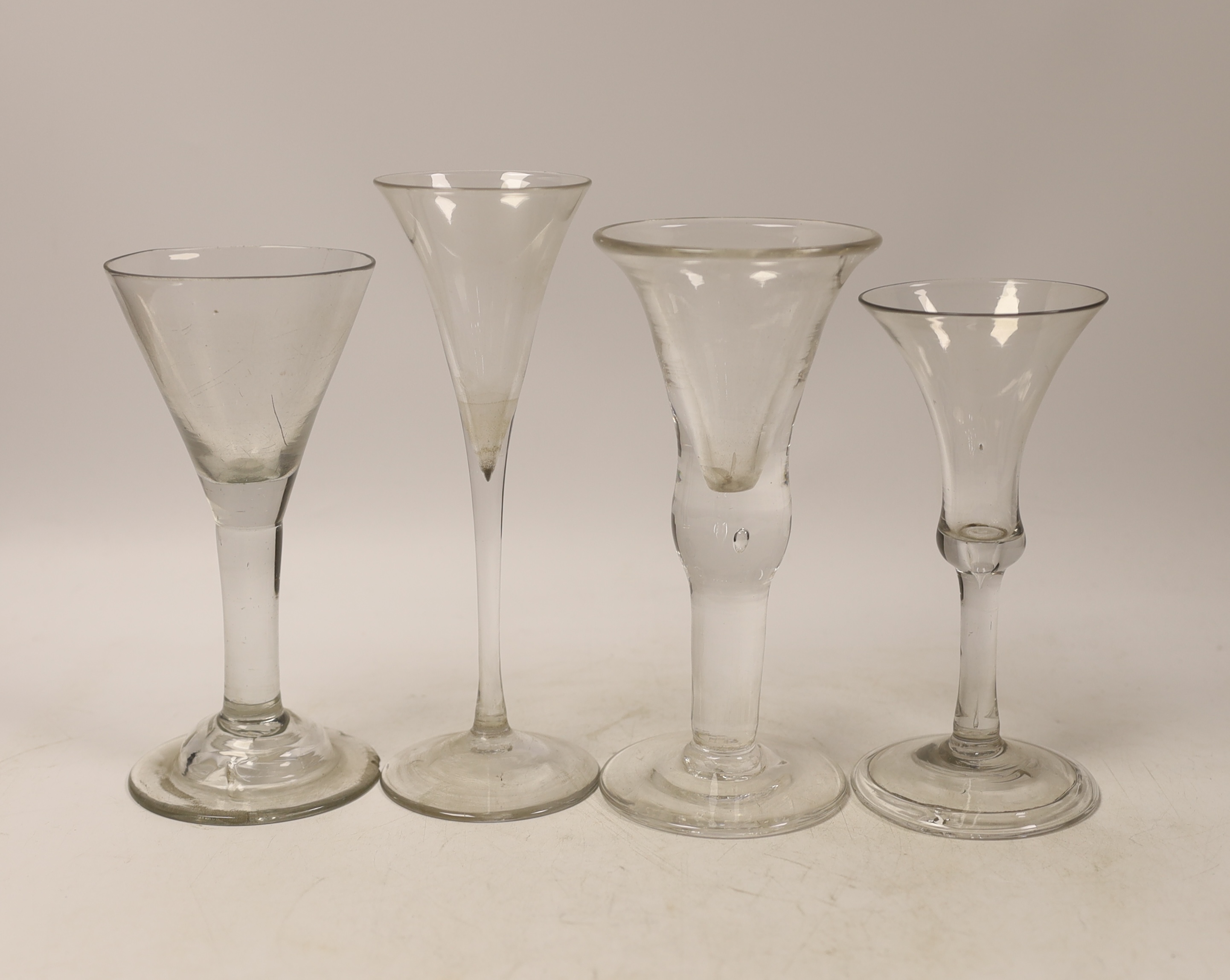 Three mid-18th century plain stem wine glasses, two with trumpet shaped bowls and a bell-shaped example with a folded foot, together with a reproduction drinking glass, tallest 20cm (4)